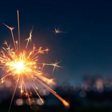 Two sparklers lit with a city skyline in the background