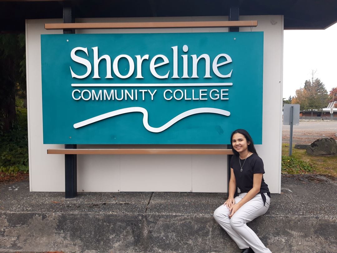 Student in front of a college sign